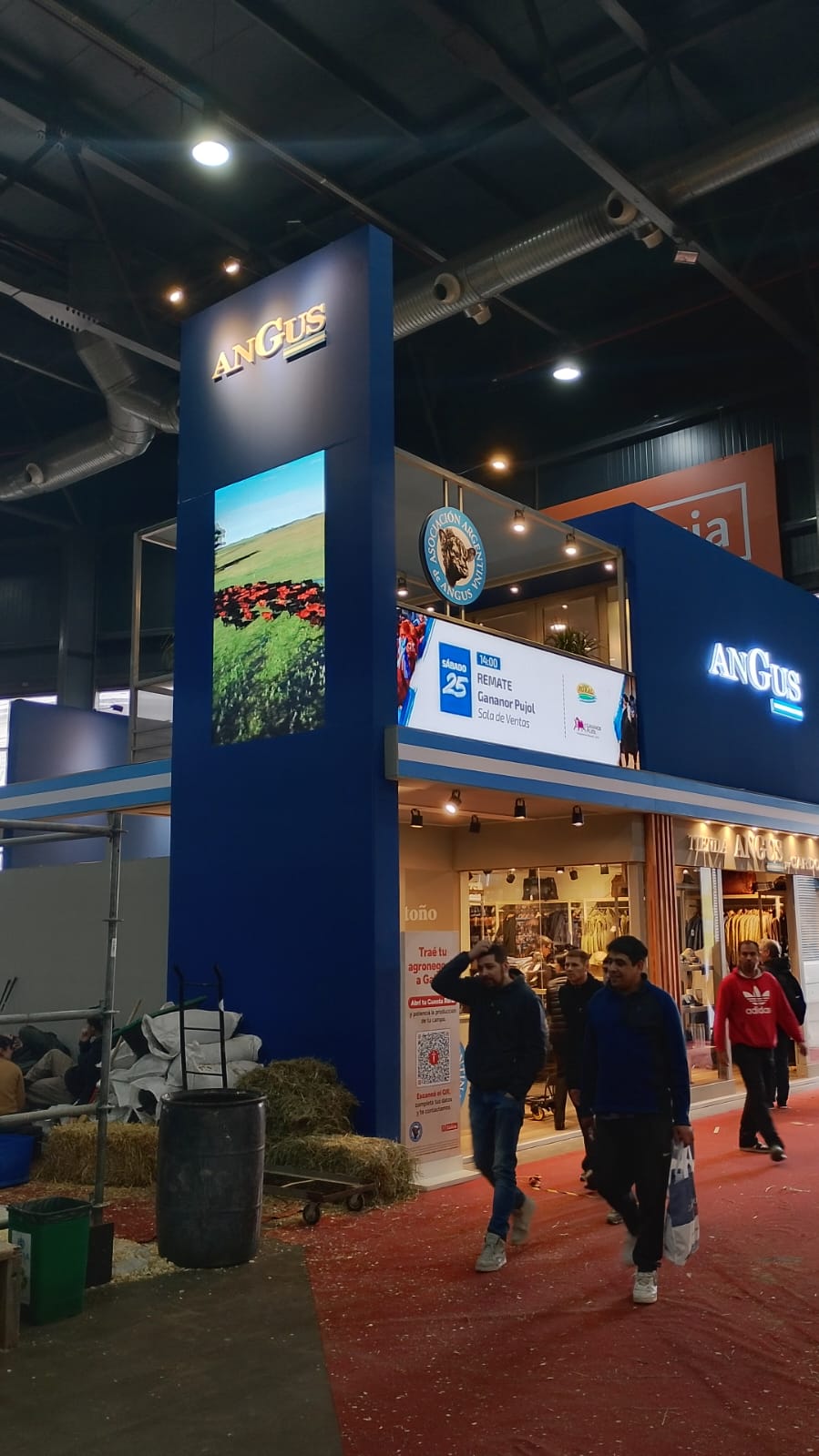Tótem LED vertical y cenefa de video horizontal con contenido en un stand azul de exposición.