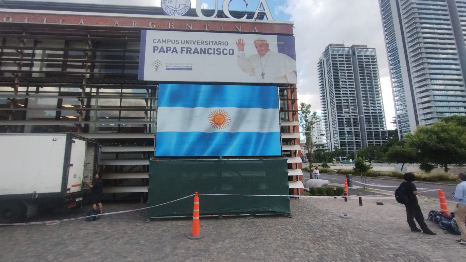 Pantalla LED exterior mostrando la bandera argentina frente a un edificio.