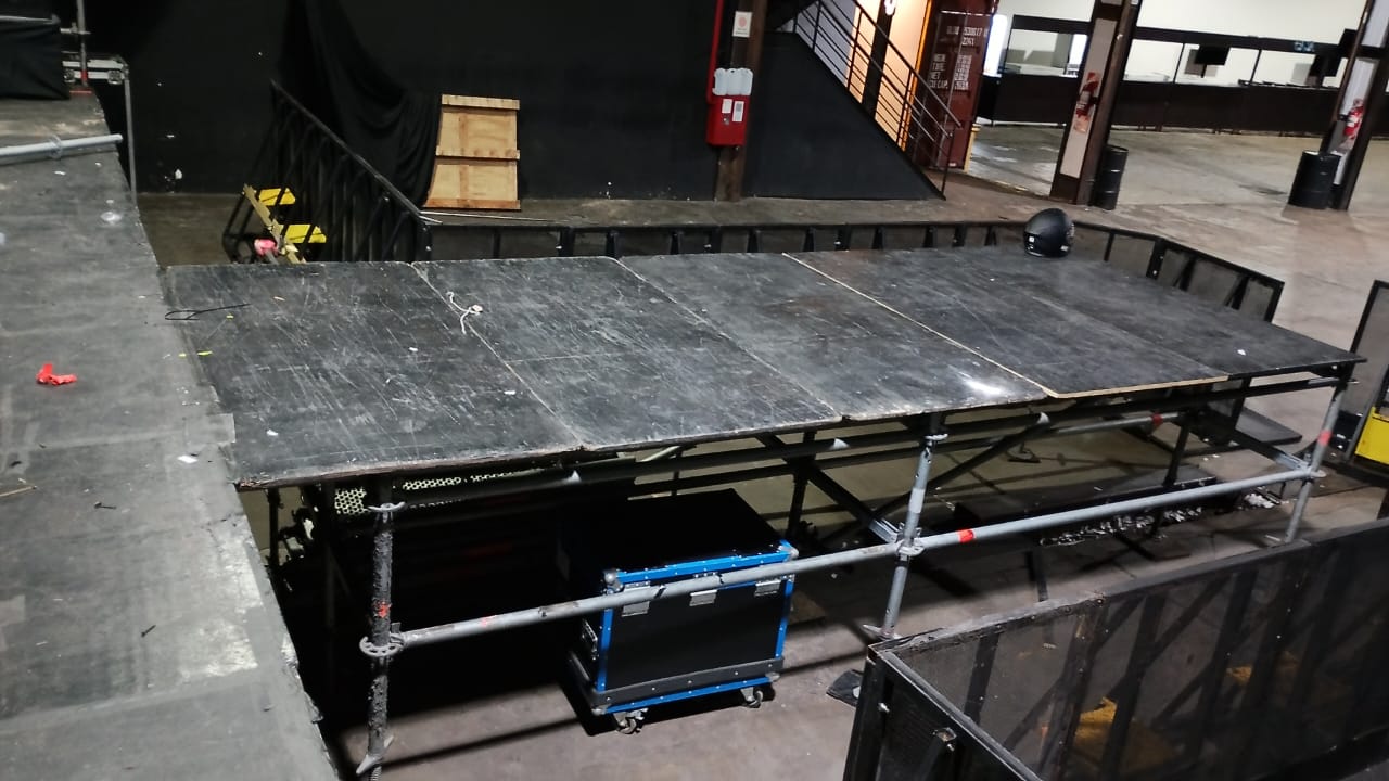 Avancée en montage près de la scène, avec plancher et structure tubulaire visibles.