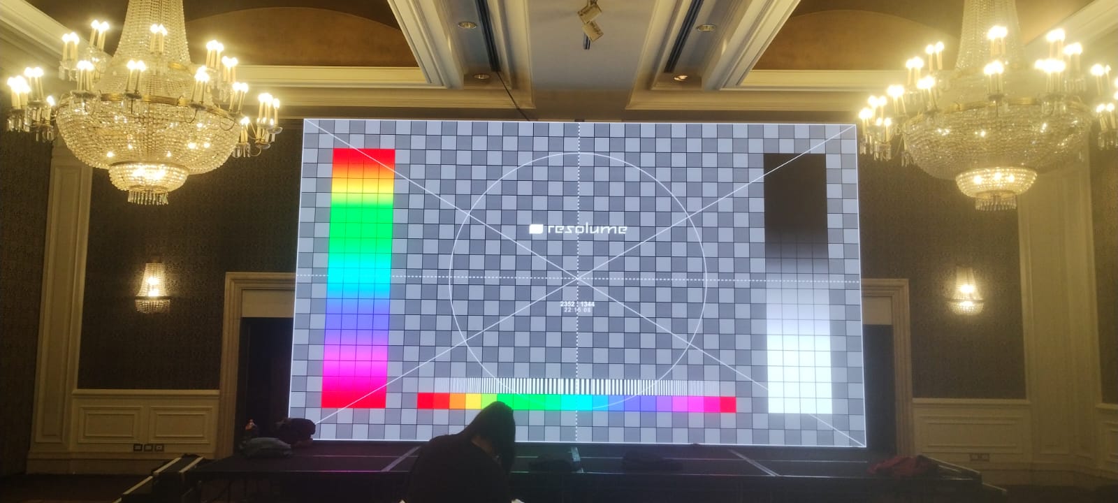 Painel LED horizontal exibindo grade e barras de cor dentro de um salão.