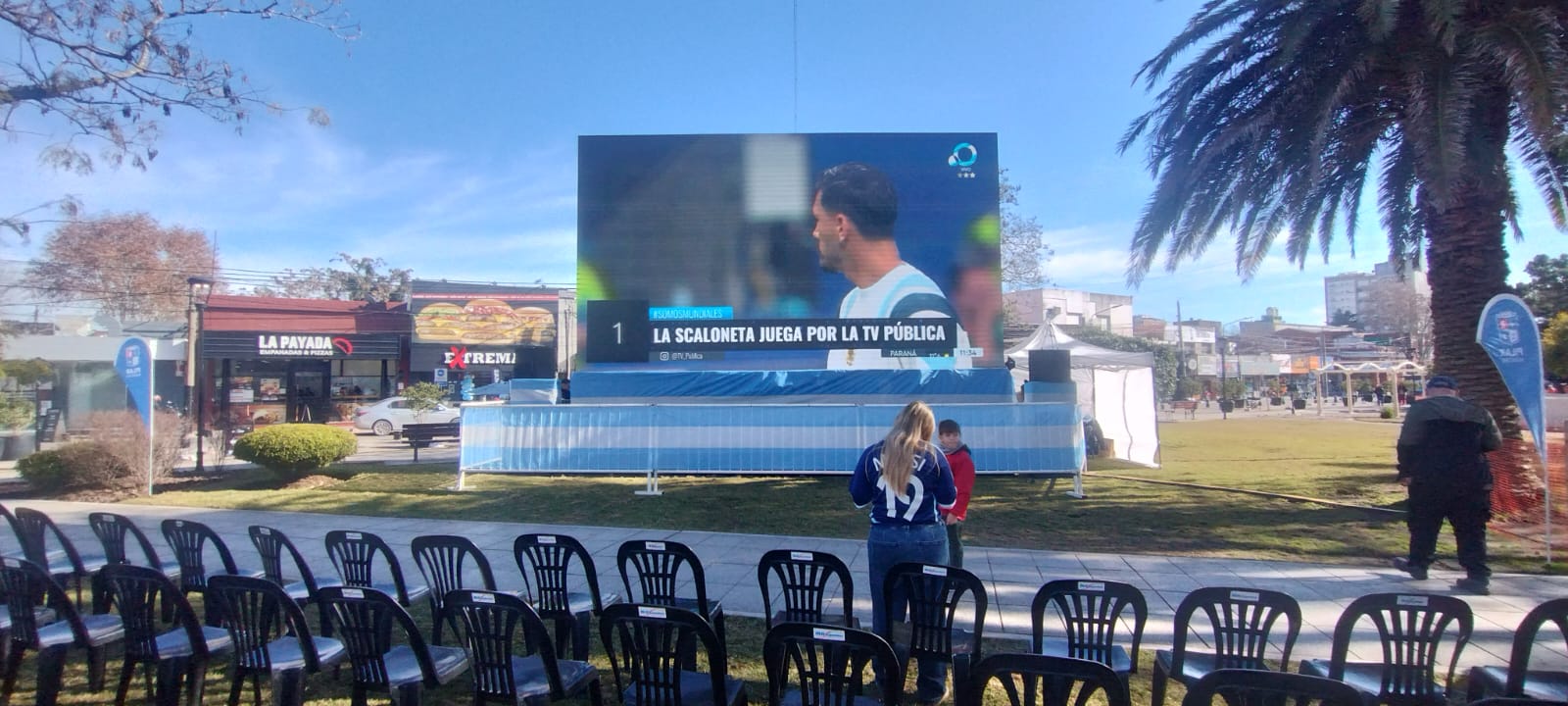 Powered LED display on grass, with rows of chairs facing the image.